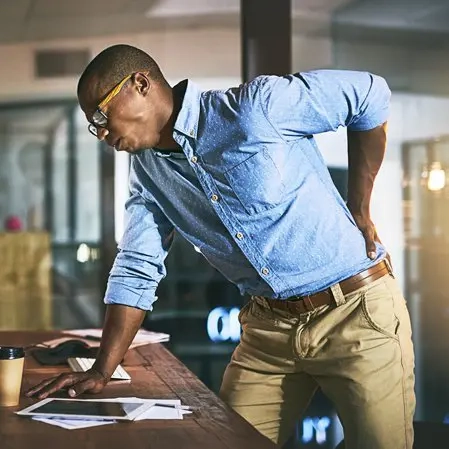 Man With Back Pain Leaning Over Desk